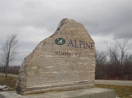 Alpine business sign with engraved lettering and logo on an upright natural stone slab