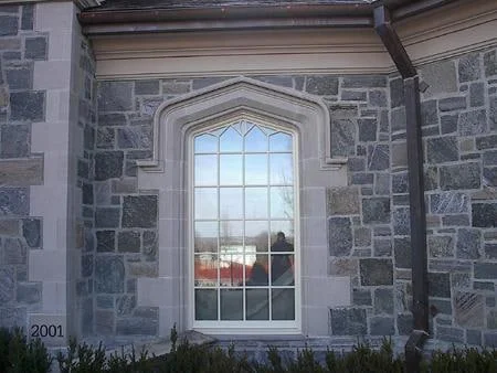 Grey granite wall around an arched window with contrasting stone trim
