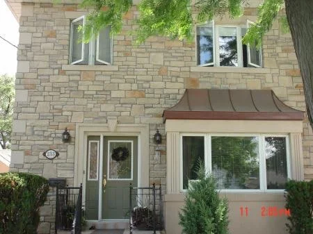 Light manufactured stone facade surrounding a residential entrance