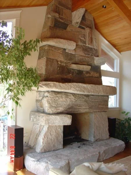 Sculptural granite fireplace with large rough stone pieces and a natural stone hearth