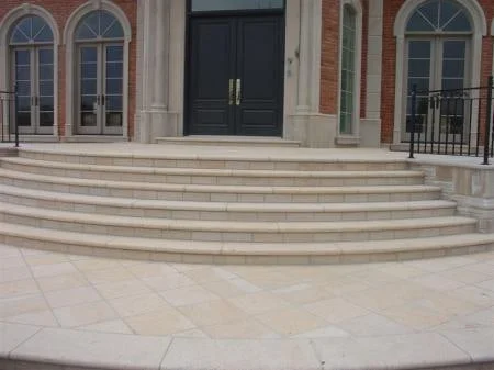 Square-cut paving meeting broad curved granite entrance steps