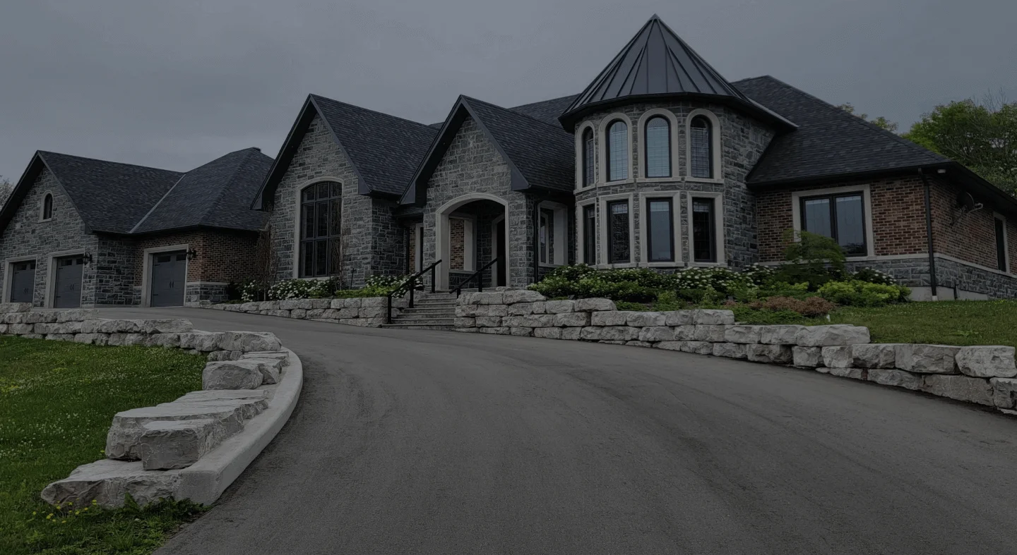 Stone-and-brick home with armour stone landscaping, with natural stone exterior detailing