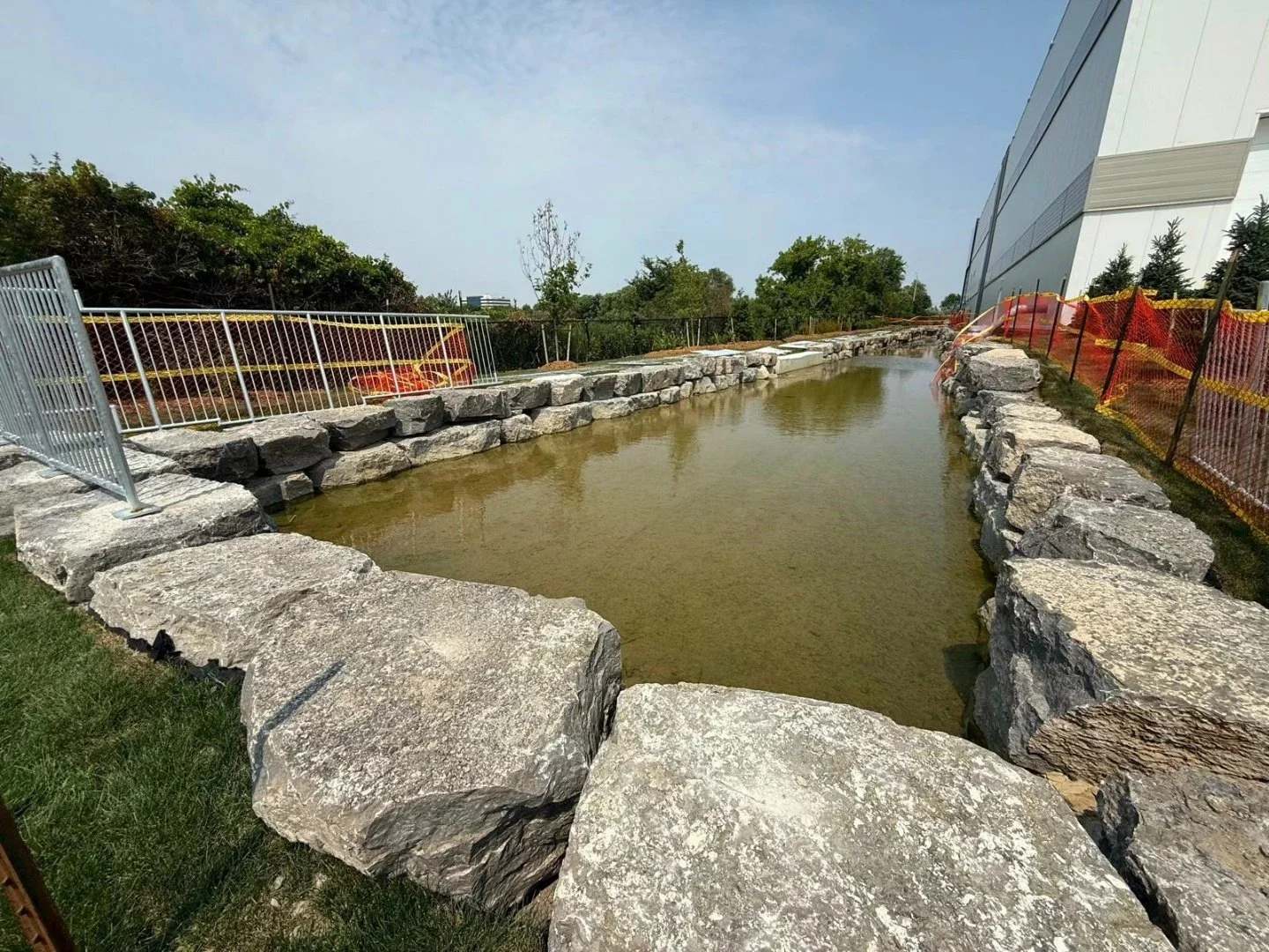 Large armour stone blocks lining a watercourse beside a construction site