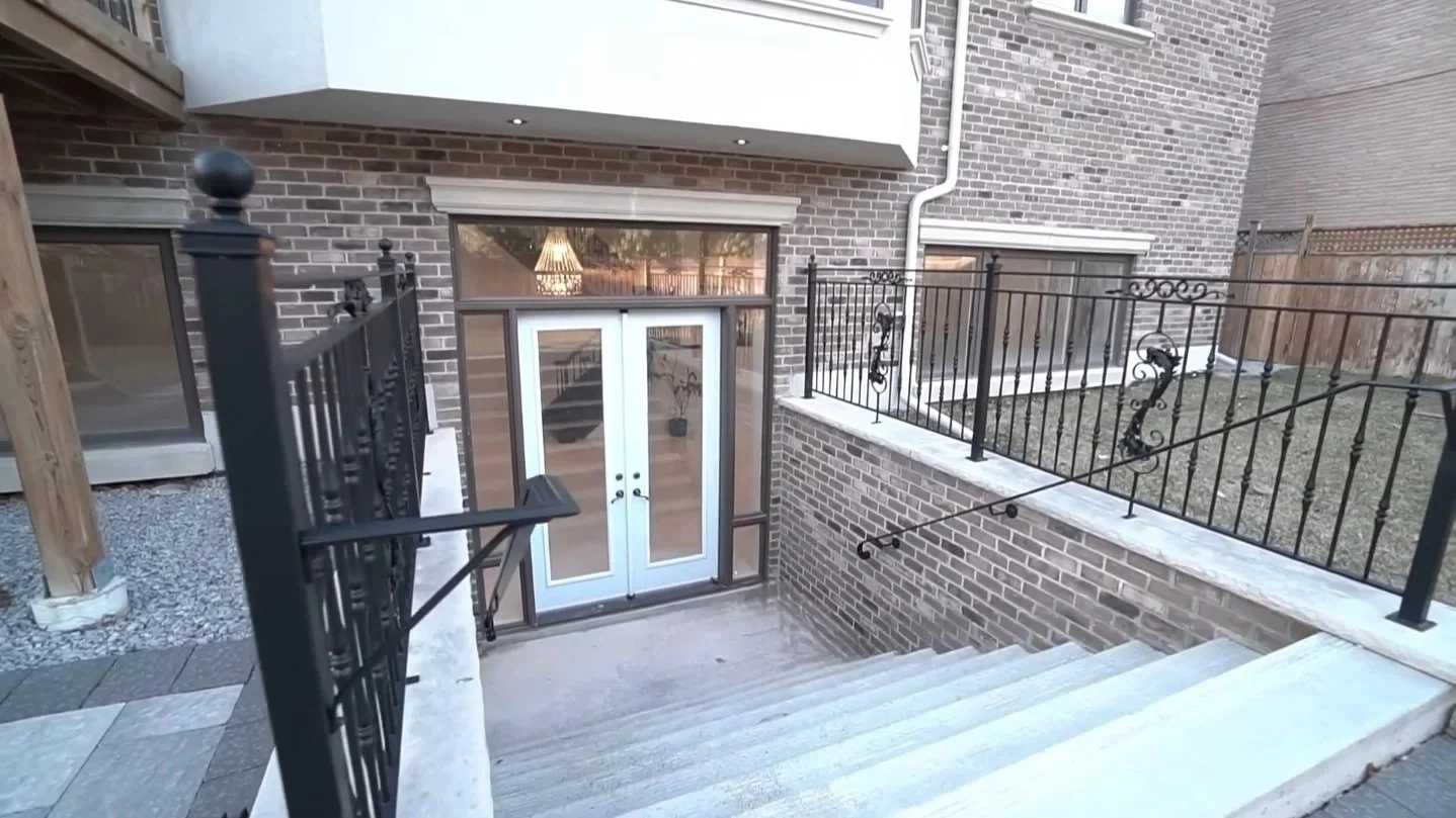 Brick house exterior and doors opening onto a lower terrace with metal railings