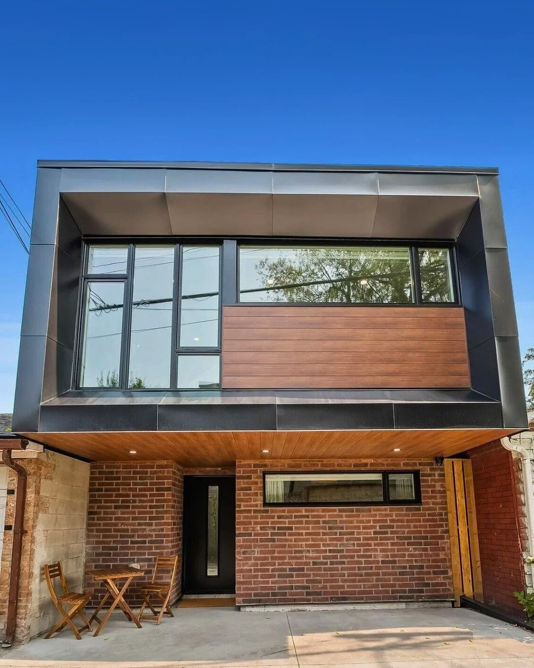 Modern home with red clay brick at ground level and dark framing above, featured as Claret brick