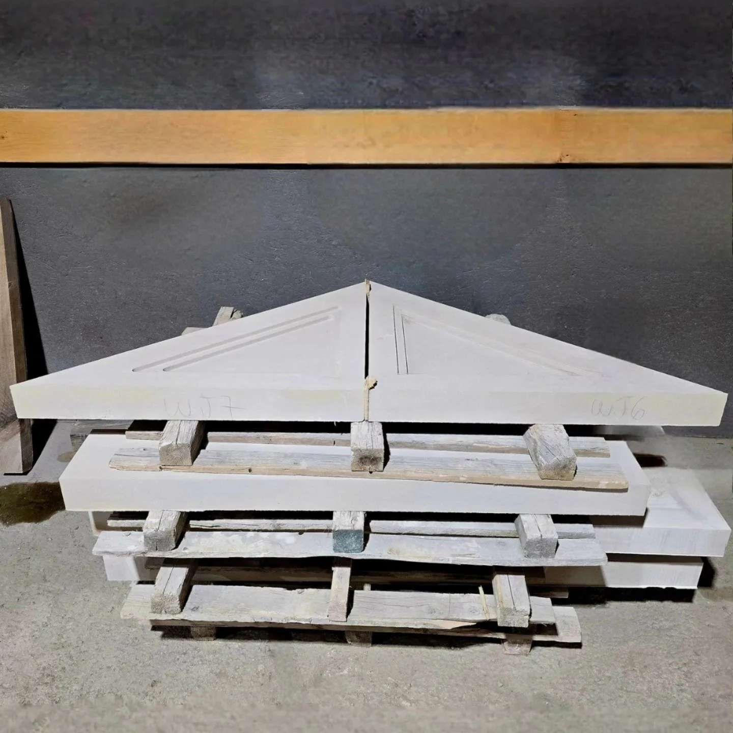 Precisely shaped pale limestone components laid out on a workshop pallet