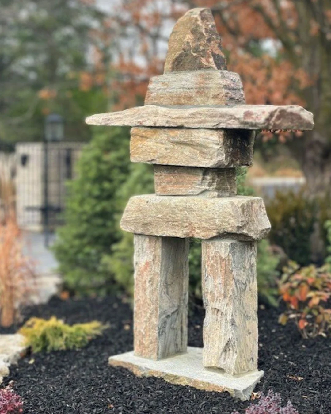 Small custom stone Inukshuk standing in a planted garden