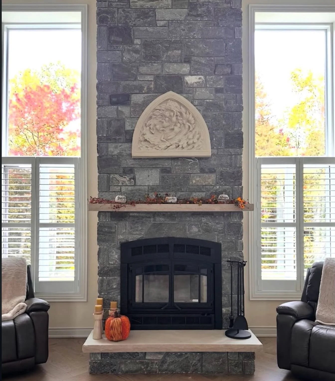 Tall fireplace with Indiana limestone mantel and hearth, darker stonework and a decorative stone panel above