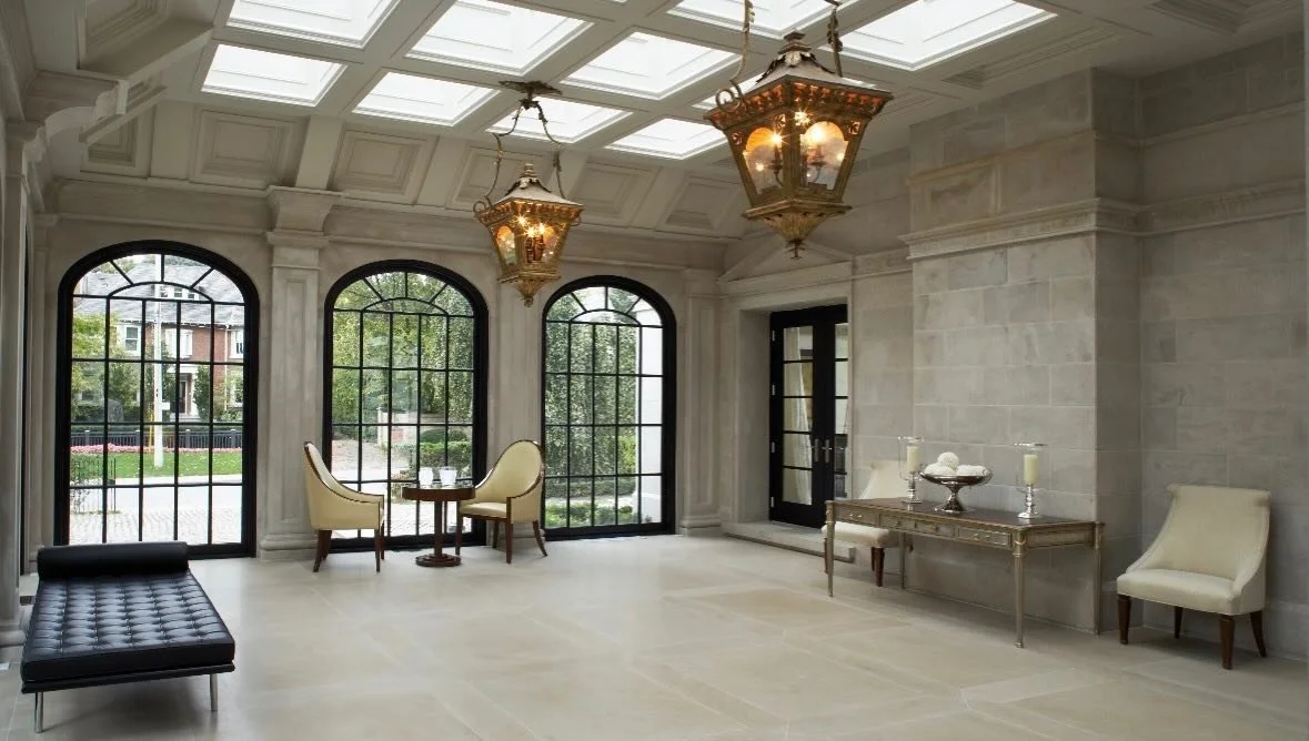 Limestone walls and columns around arched windows beneath a coffered ceiling