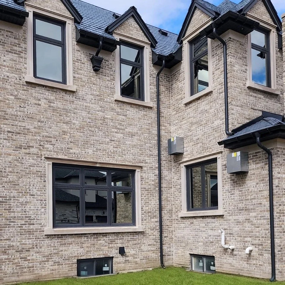 Light stone surrounds and detailing set against a brick exterior and dark-framed windows