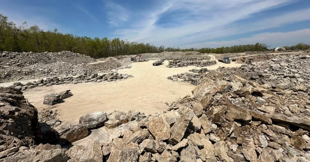 Wide view across a stone quarry with exposed rock and water