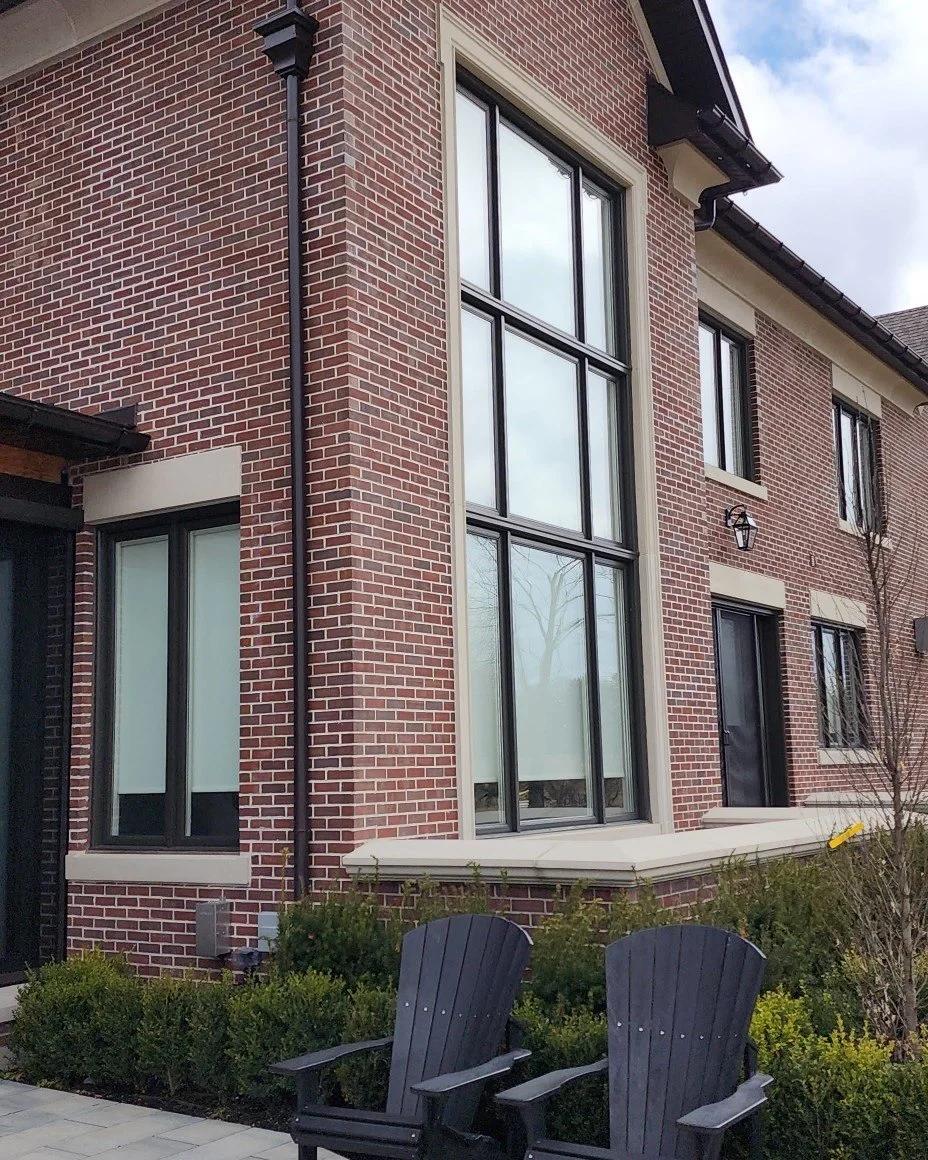 Red brick facade with tall dark-framed windows and stone lintel details
