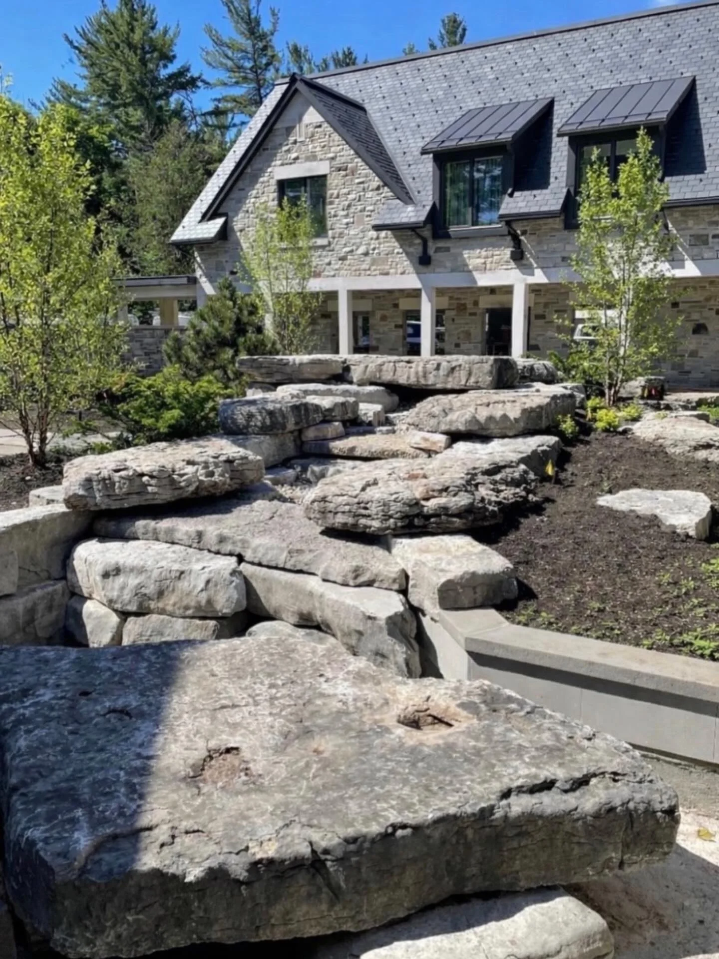 Large natural stone steps and boulders forming a landscape beside a stone house