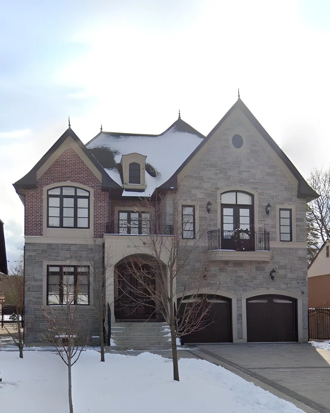 Traditional stone-and-brick house with an arched entrance and snow-covered front garden
