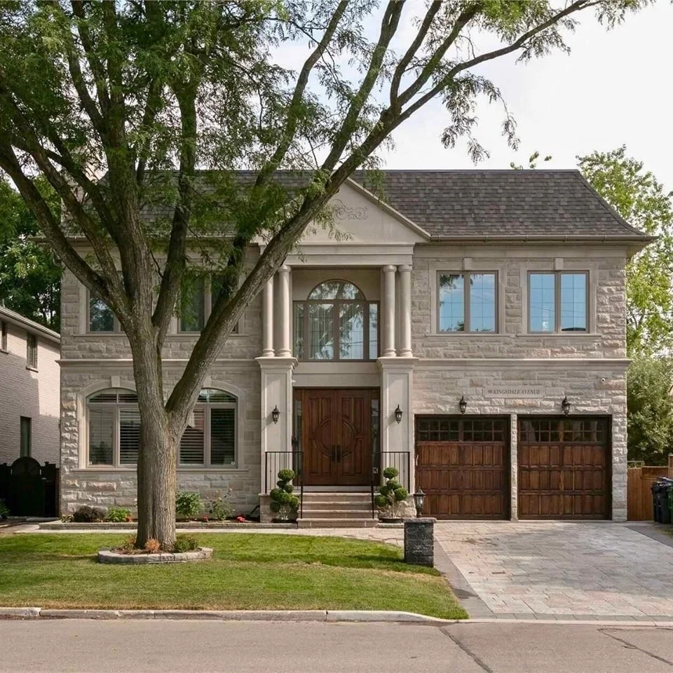 Pale stone-clad two-storey home with garage, front garden and mature street tree
