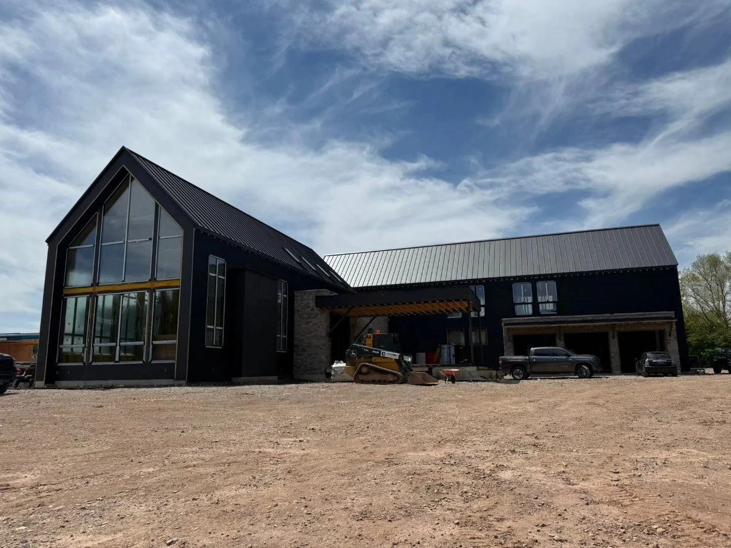 Gabled contemporary house with large windows and Woodcock Limestone Rubble, with site work still in progress