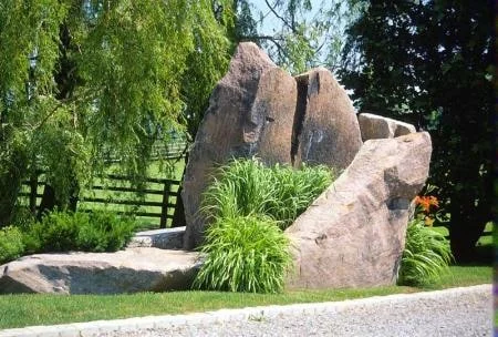 Upright Muskoka Peach granite landscape feature surrounded by planting