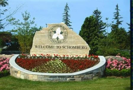 Welcome to Schomberg community sign engraved in natural stone above a landscaped stone wall
