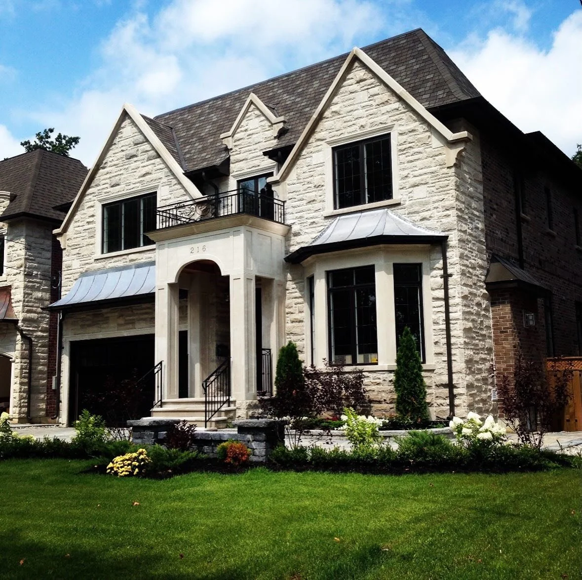 Finished stone-clad home with steep gables, bay windows and a grand arched entrance, featured by Allstone Quarry