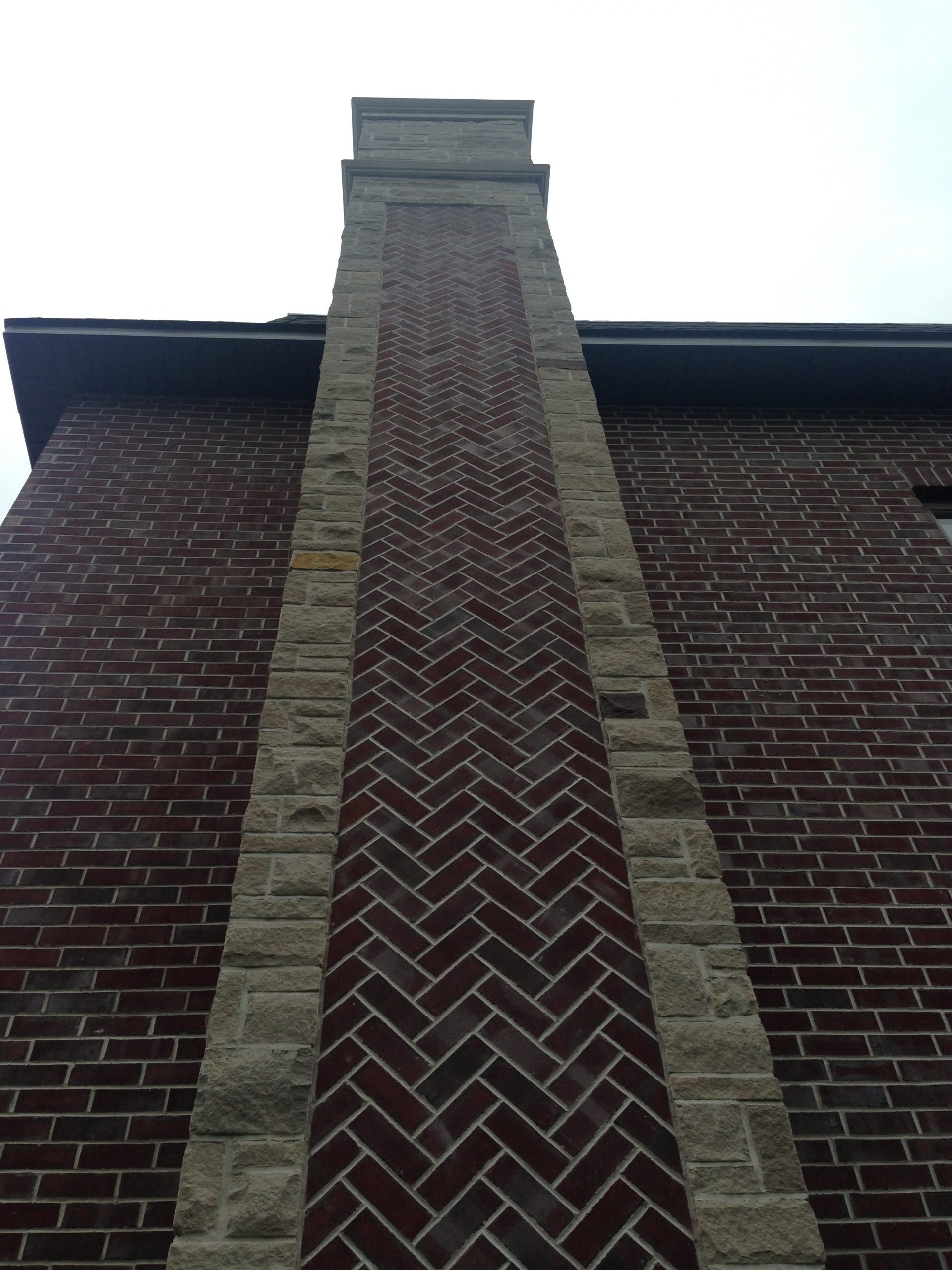 A chimney with natural stone outline and brick in a herringbone patern